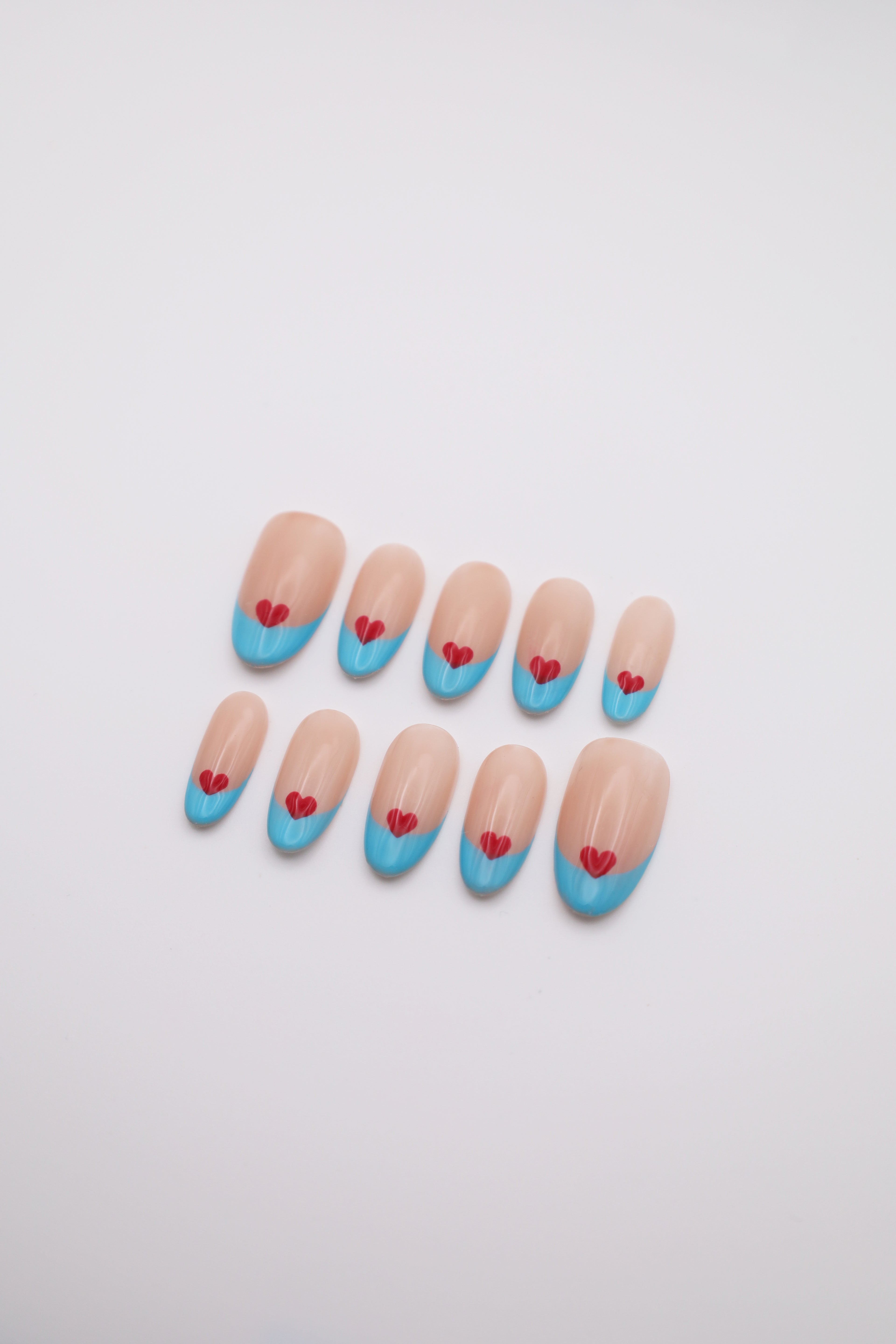 Airy Beat light blue French tip oval press-on nails set with red heart art flatlay