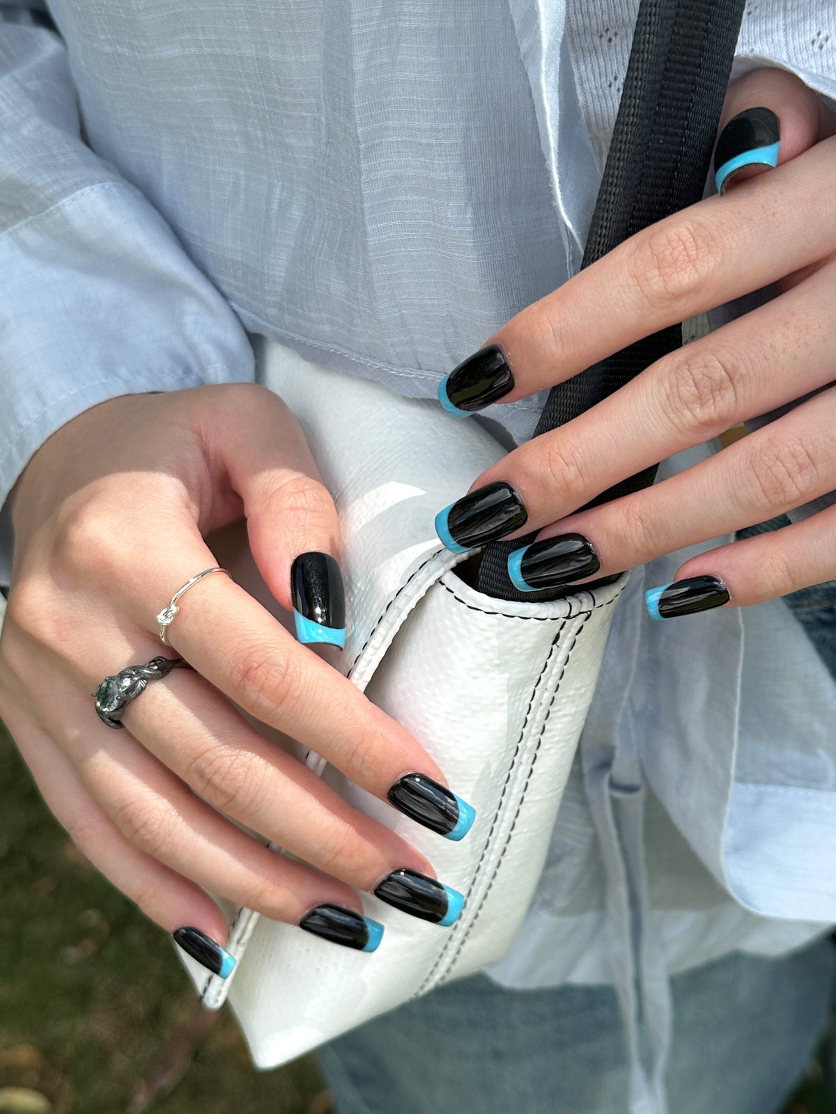 Close-up of minimalist black and sky blue reverse French square press-on nails