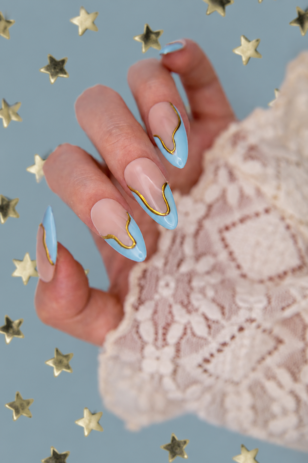 Close-up of minimalist sky blue swirl French press-on nails with metallic gold lines