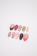Flatlay of glossy almond press-on nails with colorful pink black polka dots and stripes designs