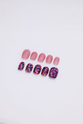 Flatlay of 10 short squoval press-on nails showing an asymmetric AB set with sheer jelly pink nails and purple gold galaxy foil glitter nails