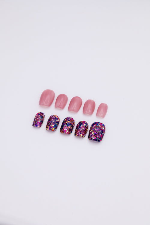 Flatlay of 10 short squoval press-on nails showing an asymmetric AB set with sheer jelly pink nails and purple gold galaxy foil glitter nails