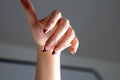 Atmospheric photo of hand wearing burgundy red swirl french almond press-on nails in dramatic lighting