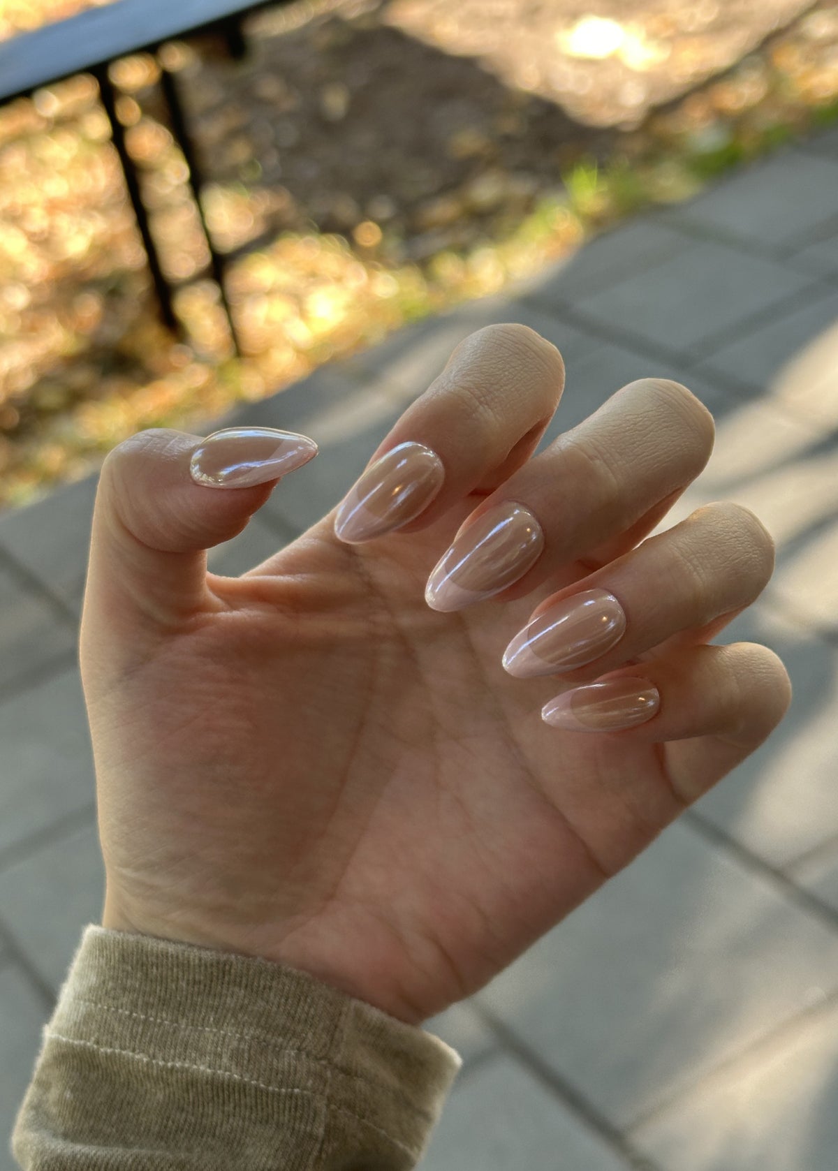 Close-up of Hailey Bieber inspired glazed chrome French manicure on short almond nails