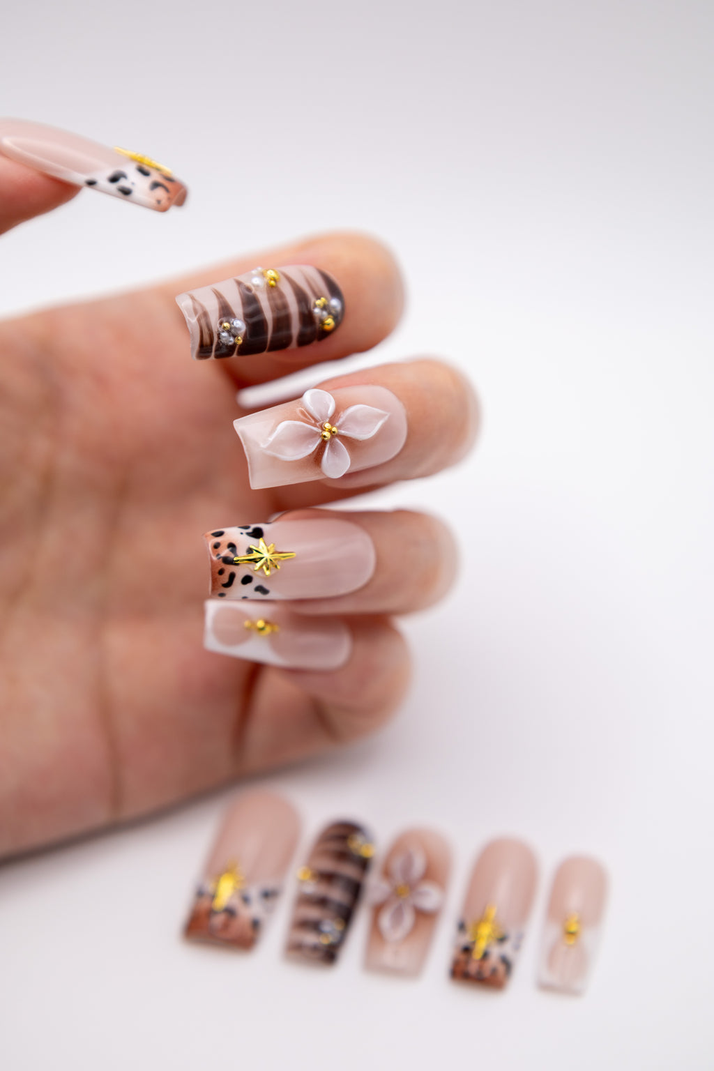 Hand showing luxury coffin press-on nails featuring 3D sculpted flower art, leopard print tips, and pearls