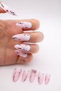 Close-up of hand wearing matte pink gradient press-on nails with 3D water drop details and ink art