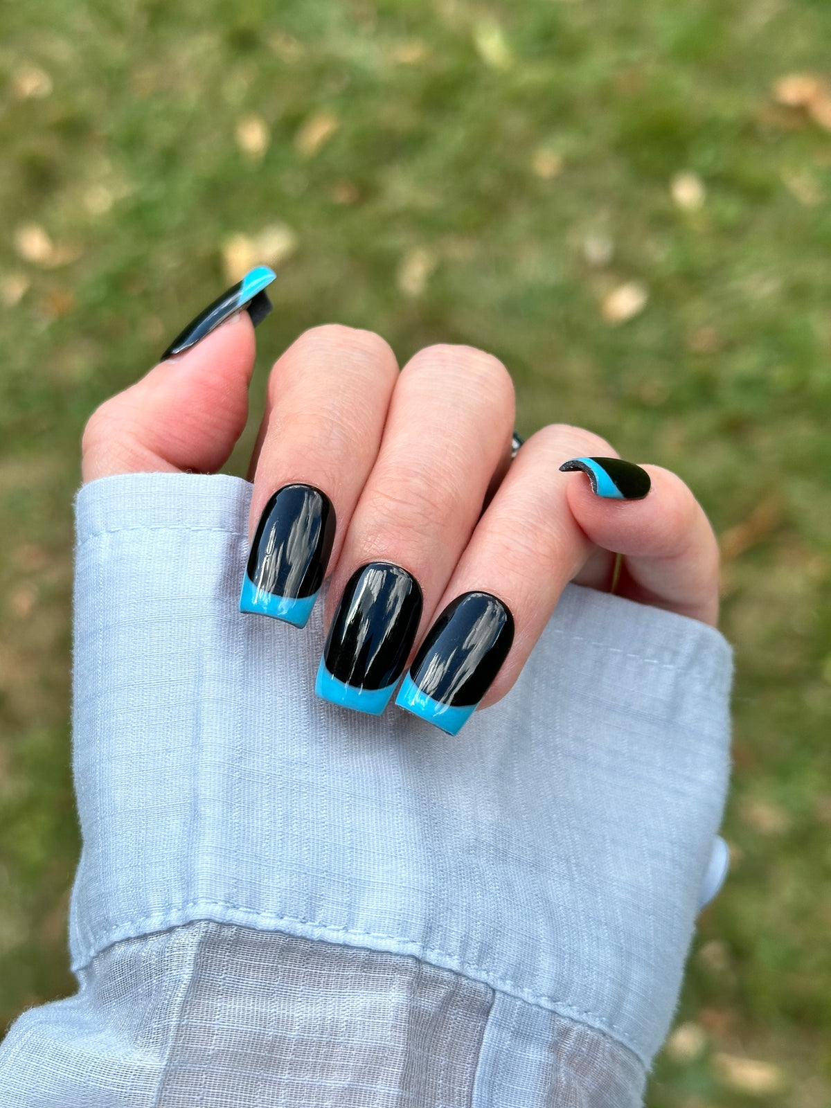 Midnight Blue glossy black square press-on nails with sky blue reverse French tips on hand