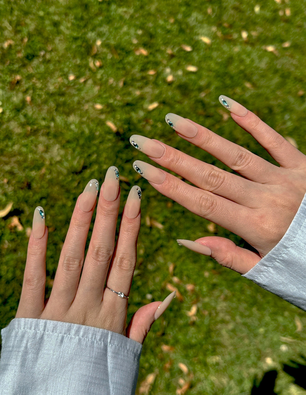 Mist Gem translucent nude press-on nails with aqua rhinestone accents on hand