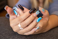Close-up of hands displaying glossy coffin press-on nails featuring 3D blue flowers, tortoiseshell pattern, and azure aura blush