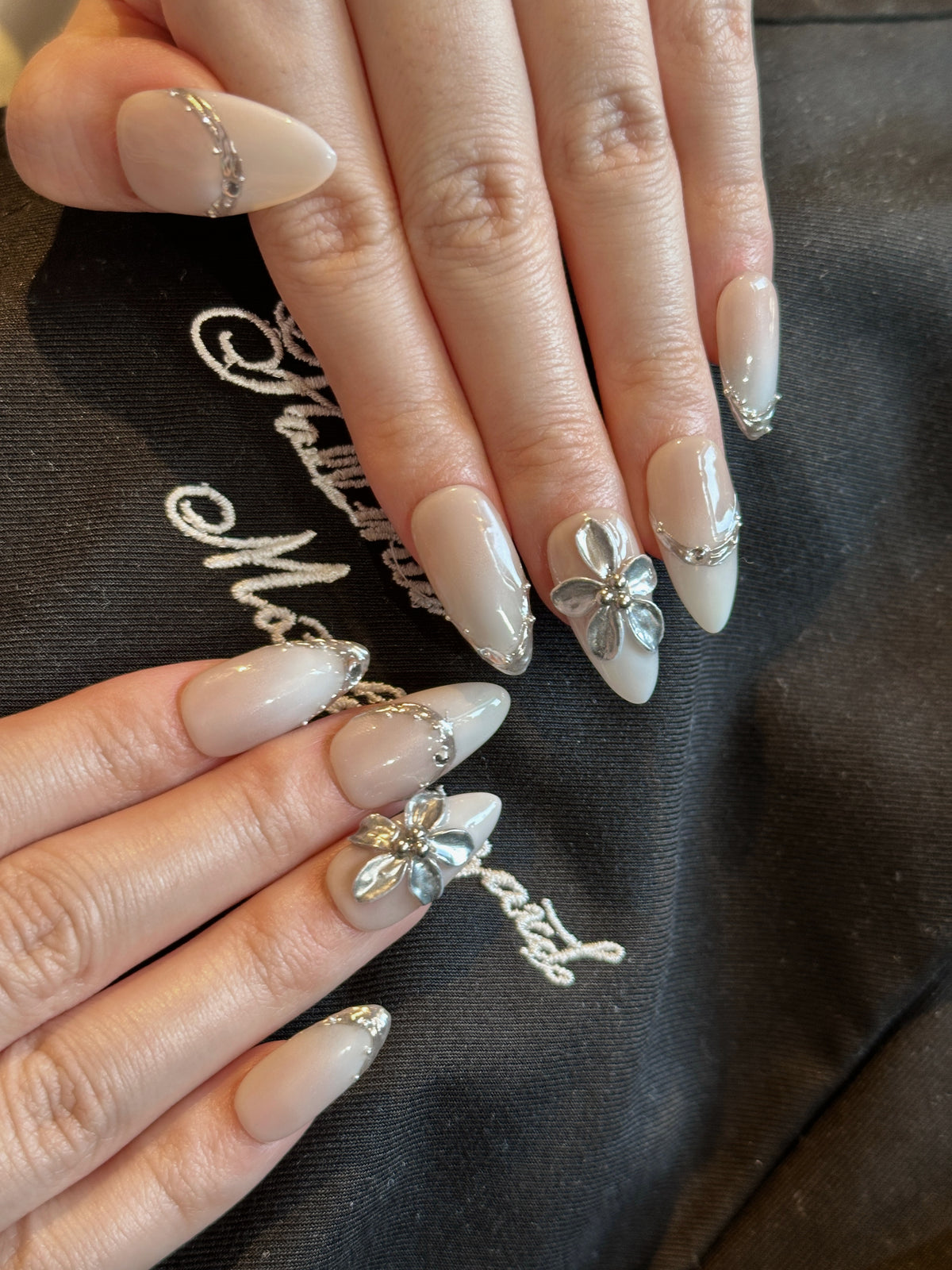 Pale Flora nude and white French ombre press-on nails with 3D silver chrome flower on hand