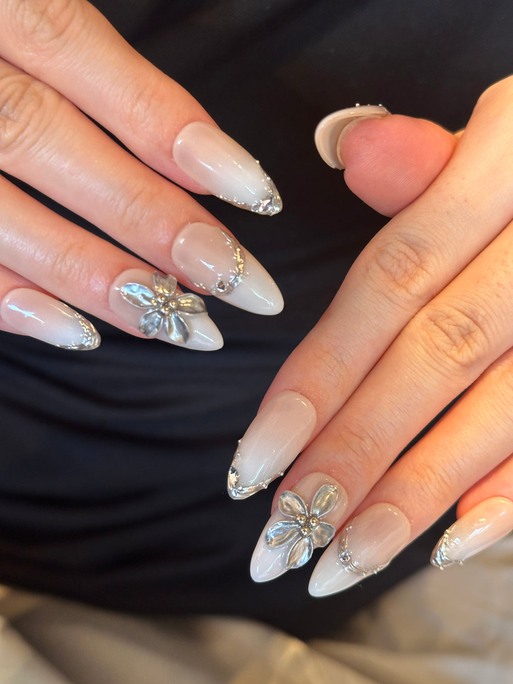 Pale Flora nude and white French ombre press-on nails with 3D silver chrome flower on hand