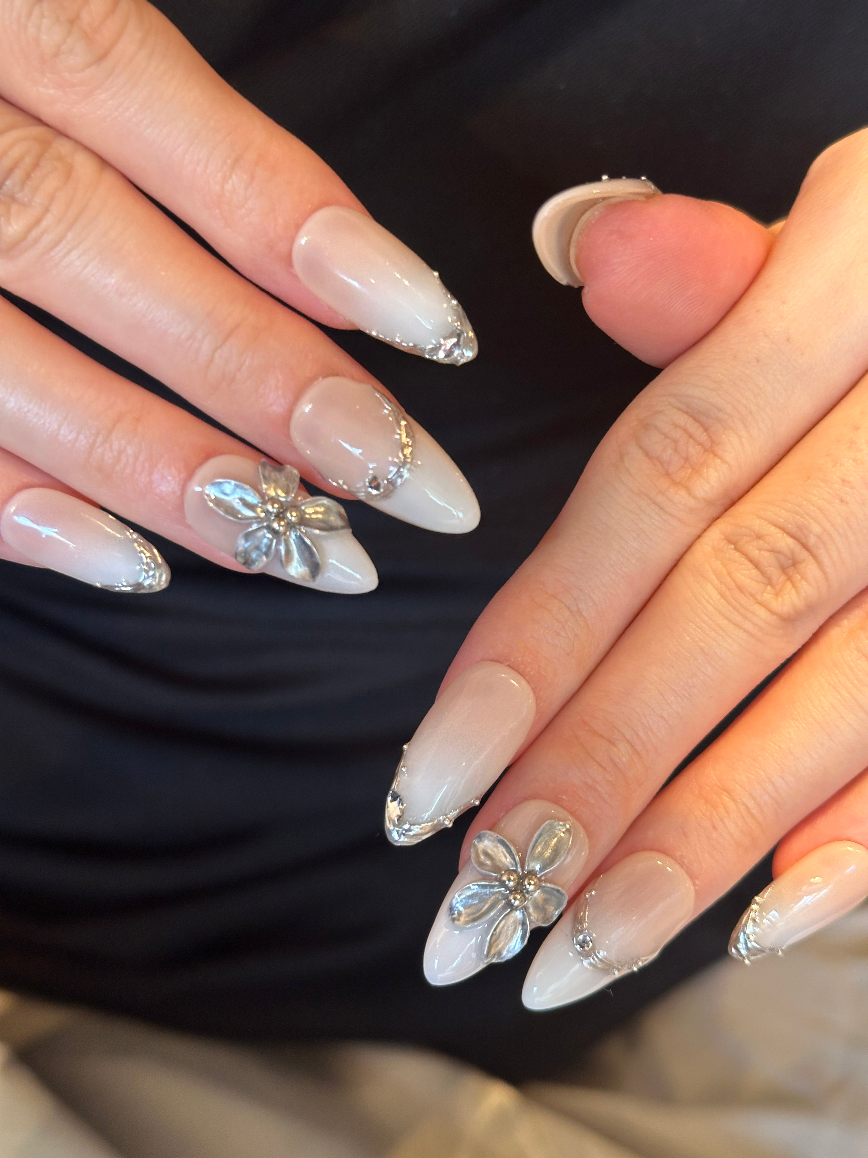 Pale Flora nude and white French ombre press-on nails with 3D silver chrome flower on hand
