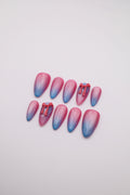 Pastel Glow pink blue ombre cat-eye almond press-on nails set with red bows flatlay