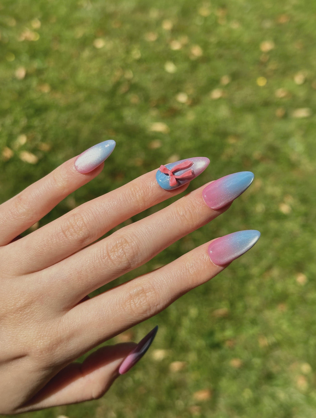 Pastel Glow pink and blue ombre cat-eye press-on nails with 3D red bows on hand