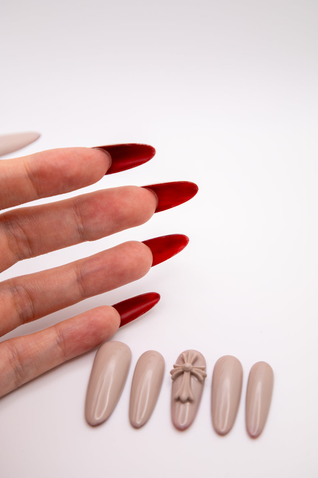 Hand showing the vibrant crimson red underside effect of taupe nude almond-shaped press-on nails