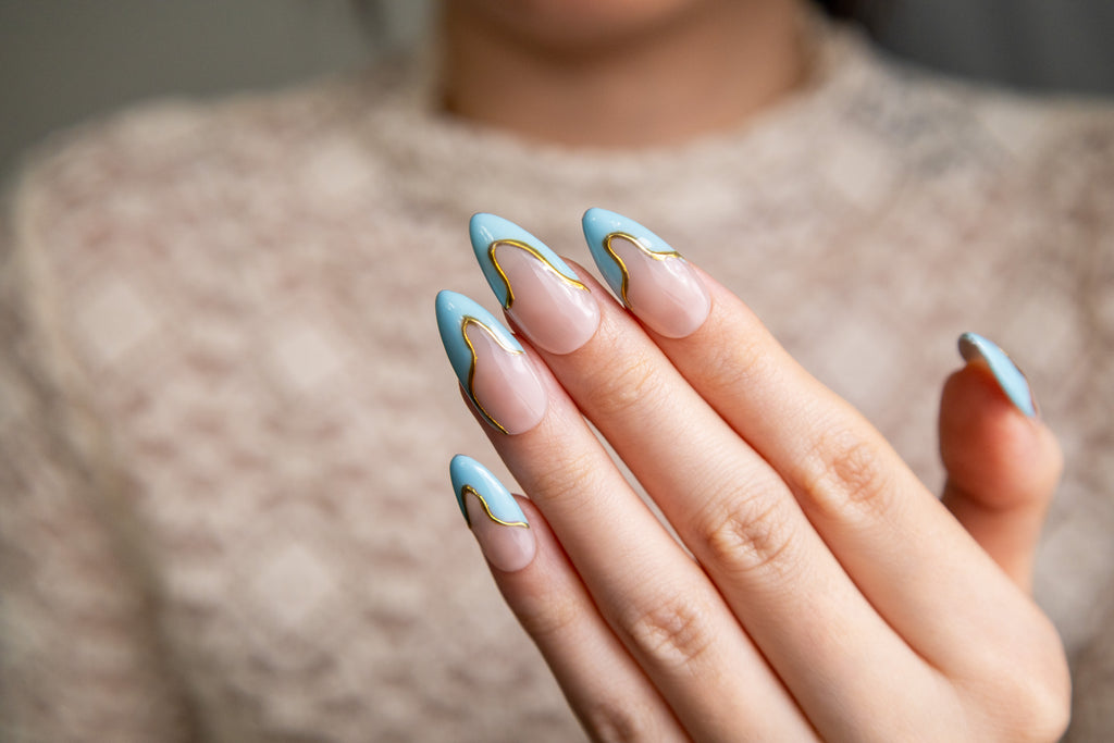 Sky Gild sky blue wavy French tip press-on nails with gold outline on hand