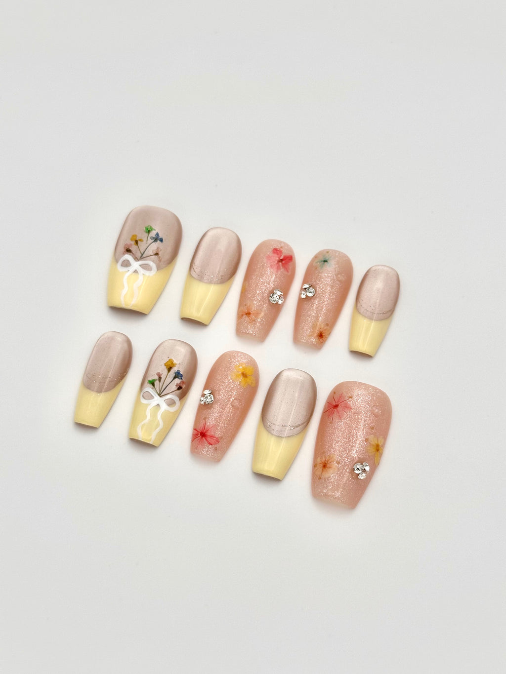Spring Dust coffin press-on nails set with yellow French tips and floral accents flatlay