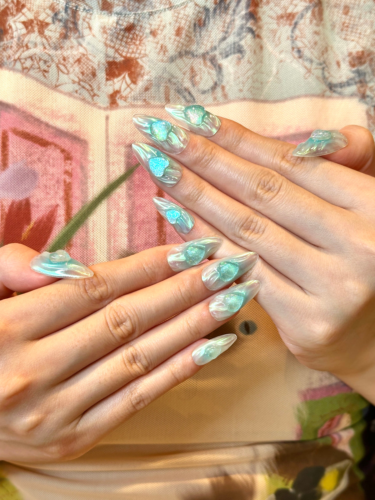 Tide Glow translucent teal water ripple press-on nails with 3D glitter hearts on hand