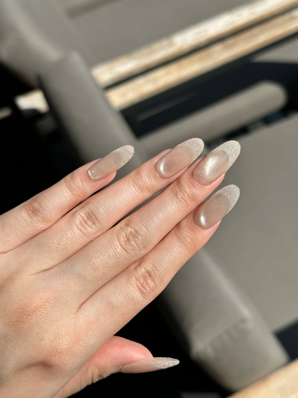 Close-up of nude and black velvet cat-eye press-on nails with shiny French tip details