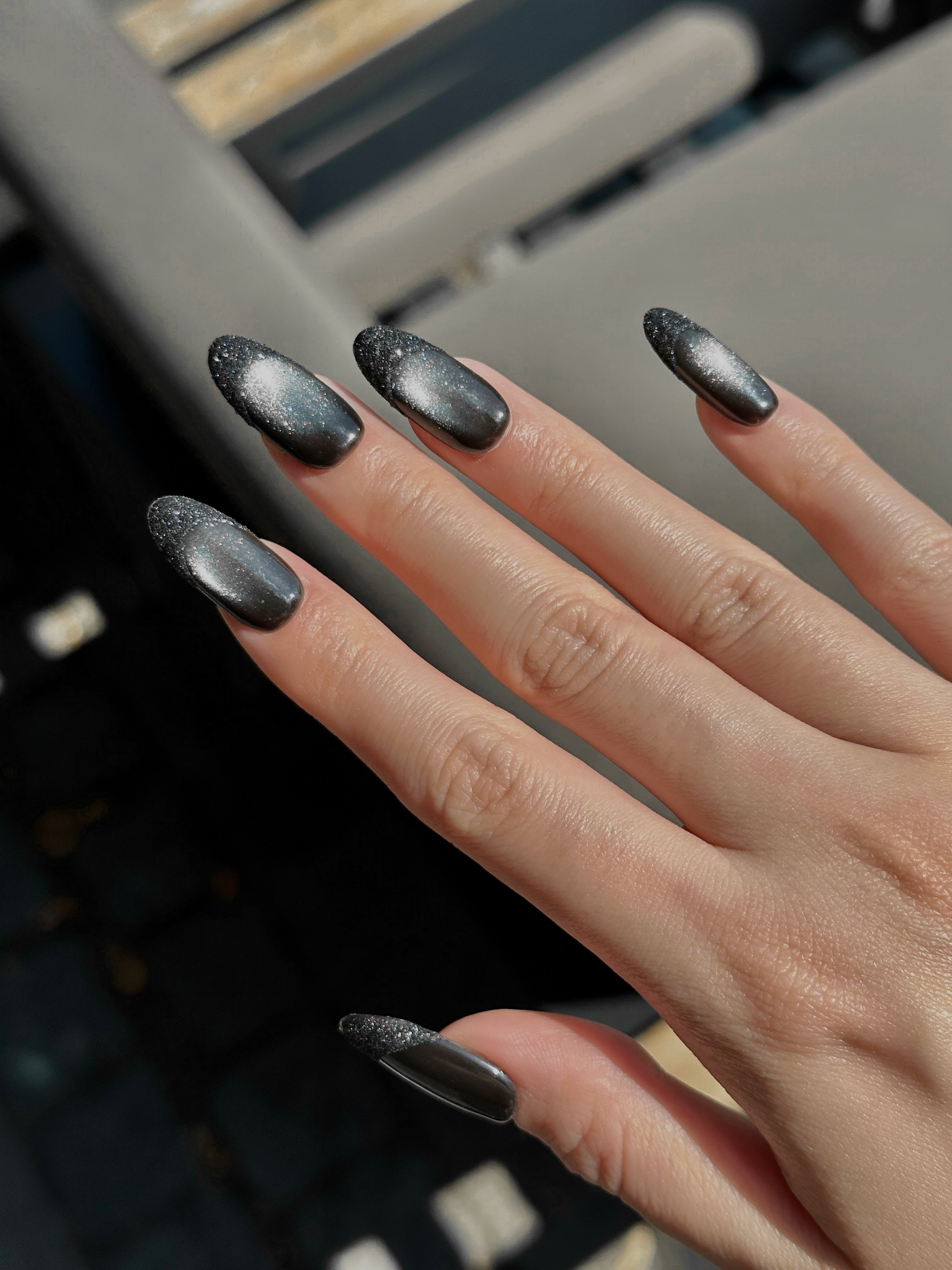 Close-up of nude and black velvet cat-eye press-on nails with shiny French tip details